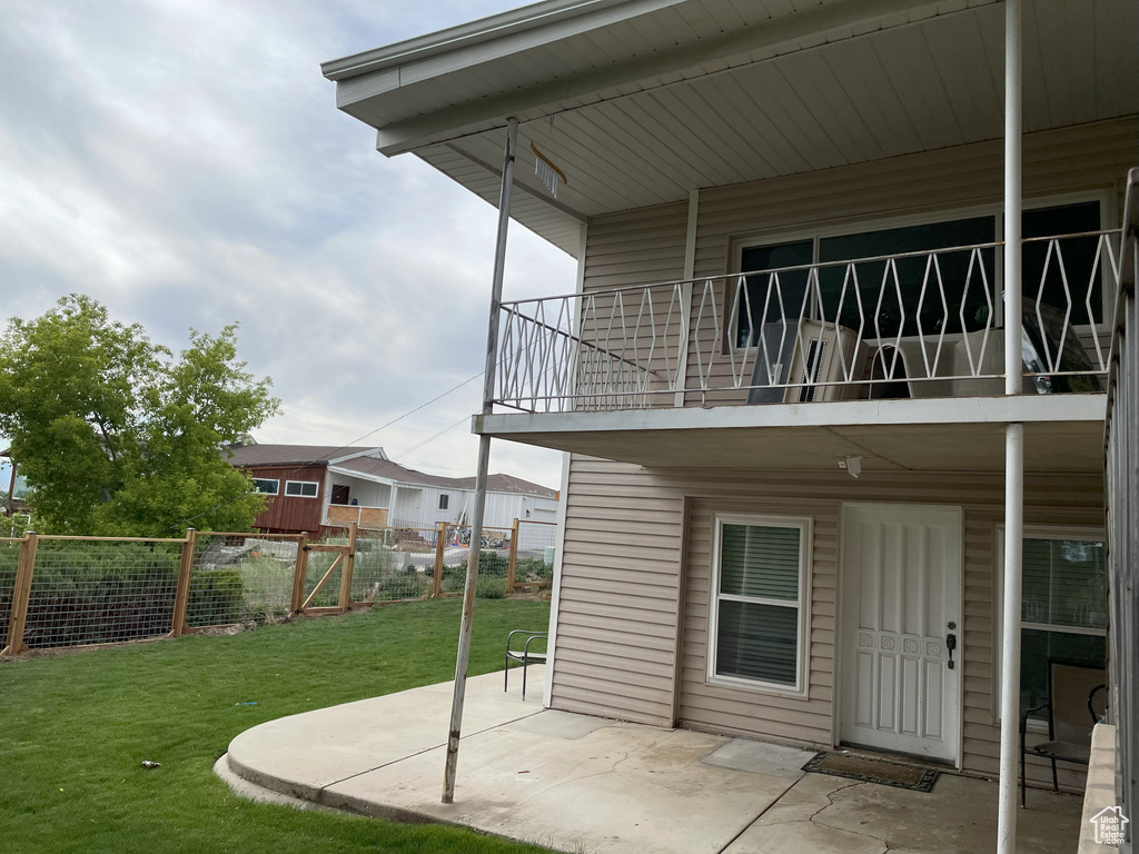 Rear view of property featuring a patio area, a yard, and a balcony