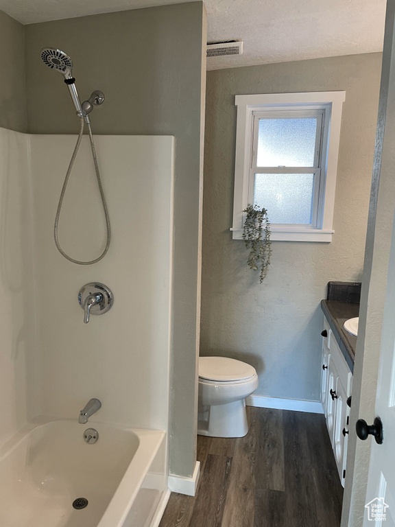 Full bathroom featuring hardwood / wood-style floors, a textured ceiling, toilet, shower / bathtub combination, and vanity