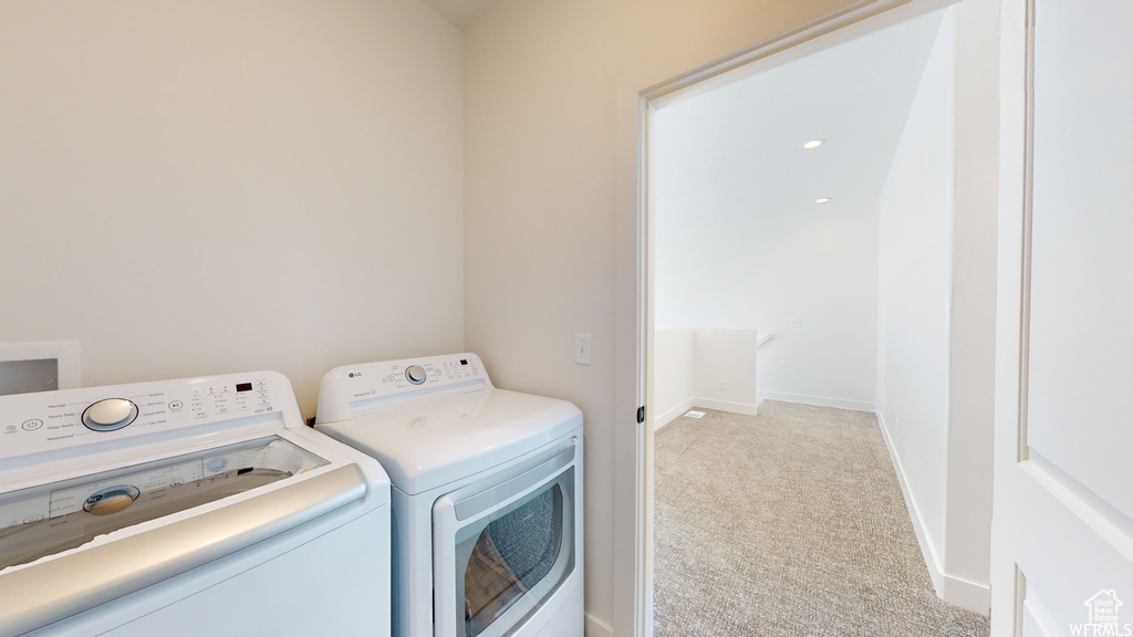 Laundry room with washer hookup, light colored carpet, and washing machine and clothes dryer