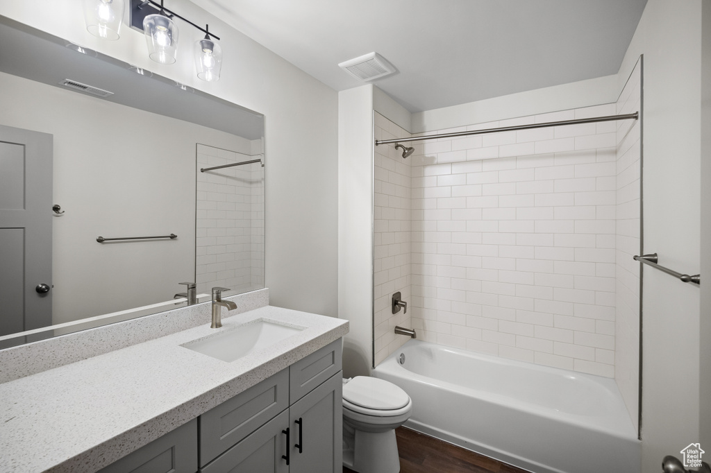 Full bathroom featuring hardwood / wood-style flooring, vanity, toilet, and tiled shower / bath