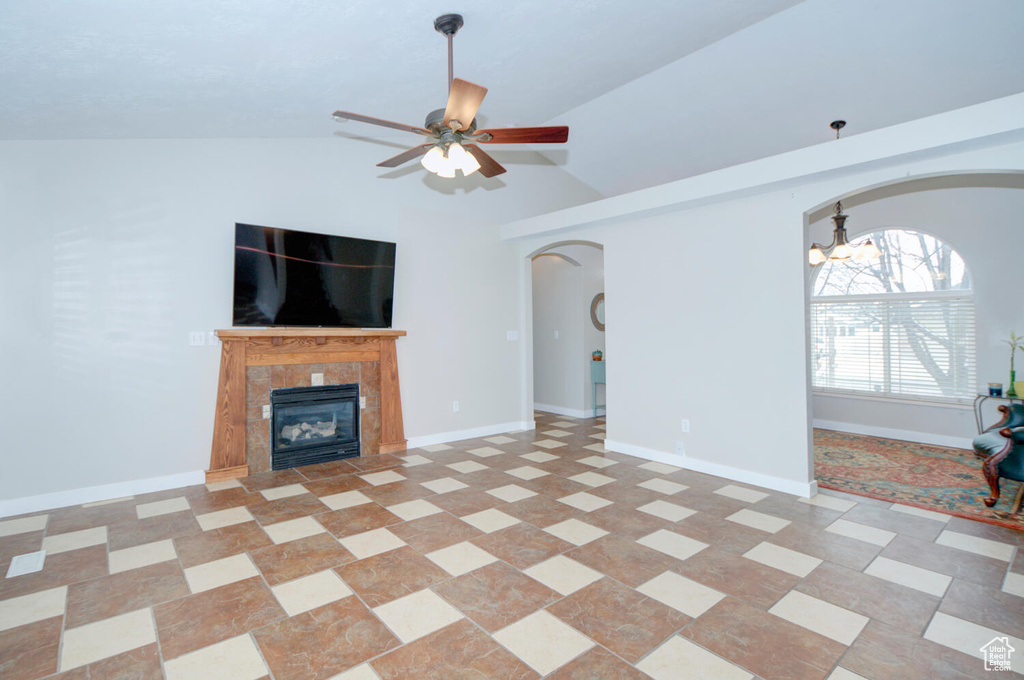 Unfurnished living room featuring ceiling fan, light tile floors, lofted ceiling, and a tile fireplace