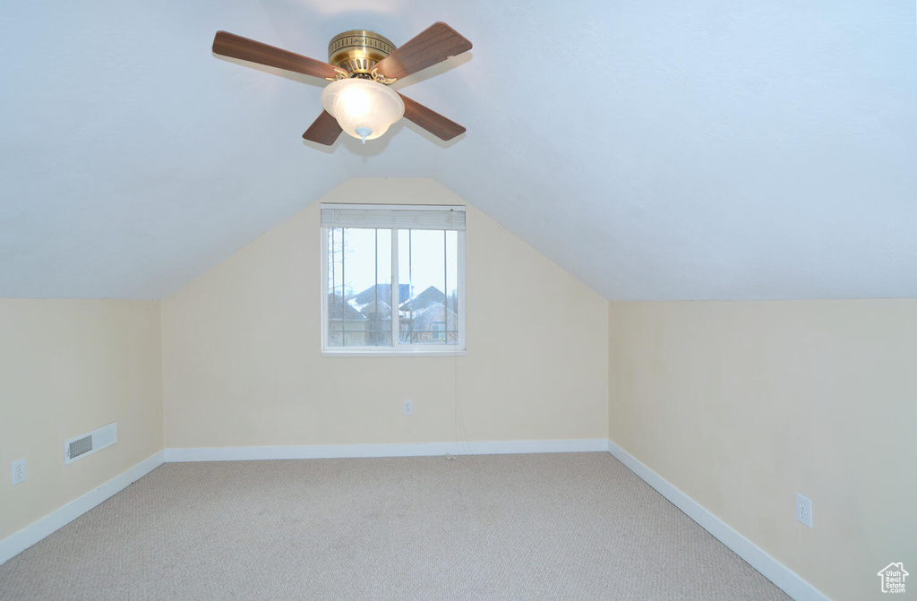 Bonus room with vaulted ceiling, light colored carpet, and ceiling fan
