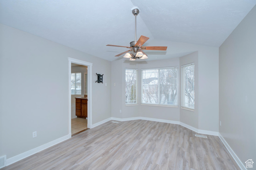 Spare room with vaulted ceiling, light hardwood / wood-style flooring, and ceiling fan