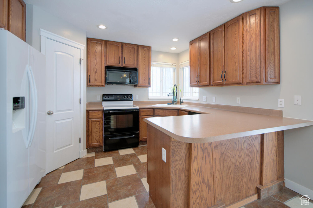 Kitchen featuring sink, kitchen peninsula, white appliances, and light tile floors