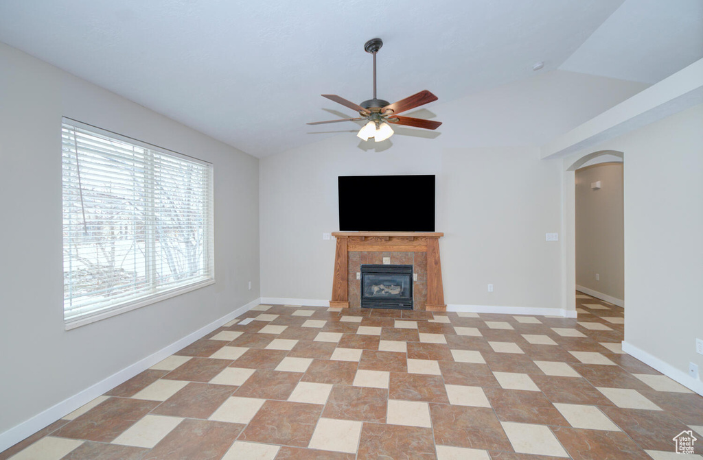 Unfurnished living room featuring lofted ceiling, a tile fireplace, light tile floors, and ceiling fan