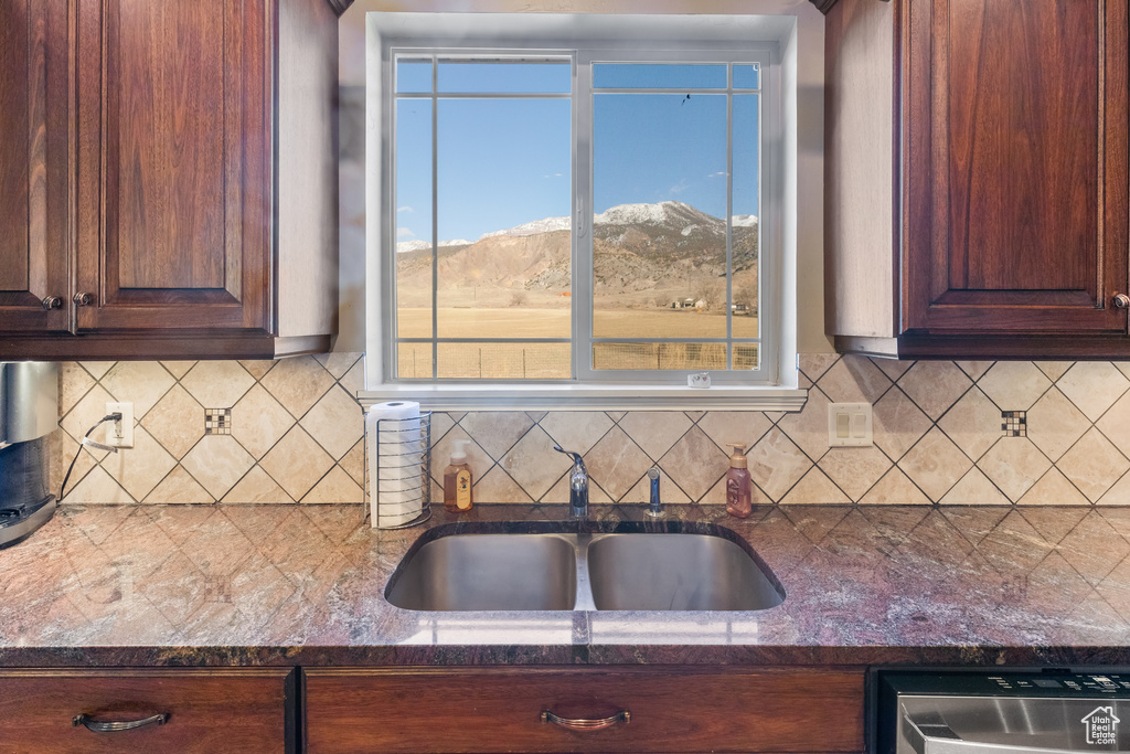 Kitchen with tasteful backsplash, a mountain view, stainless steel dishwasher, dark stone counters, and sink