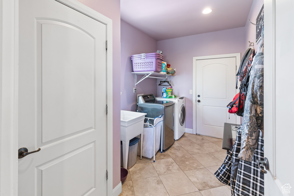Laundry area featuring independent washer and dryer, light tile flooring, and sink