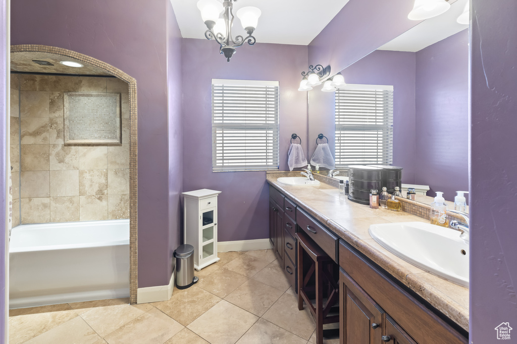 Bathroom with a chandelier, double sink vanity, tile floors, and a tub