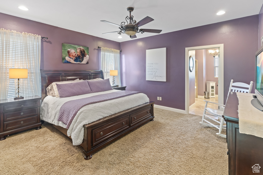Bedroom featuring light carpet and ceiling fan with notable chandelier