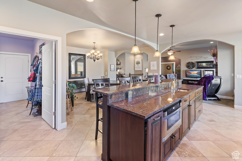 Kitchen with dark stone counters, light tile floors, a kitchen breakfast bar, and hanging light fixtures