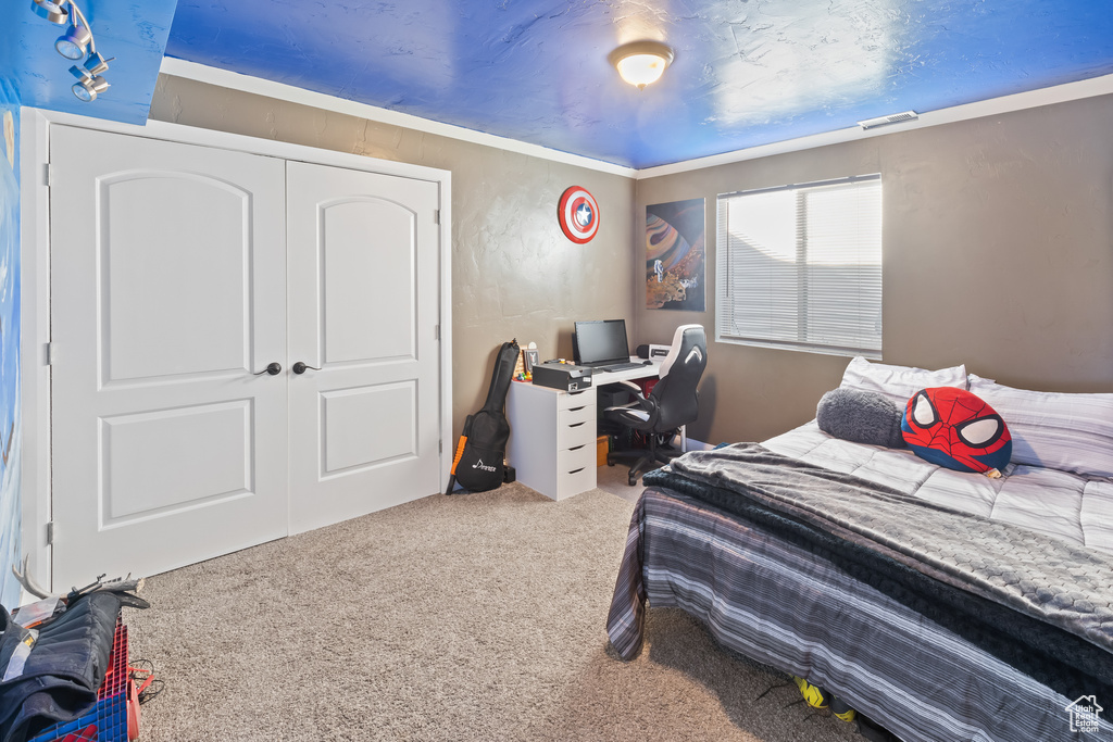 Bedroom with ornamental molding, a closet, and carpet