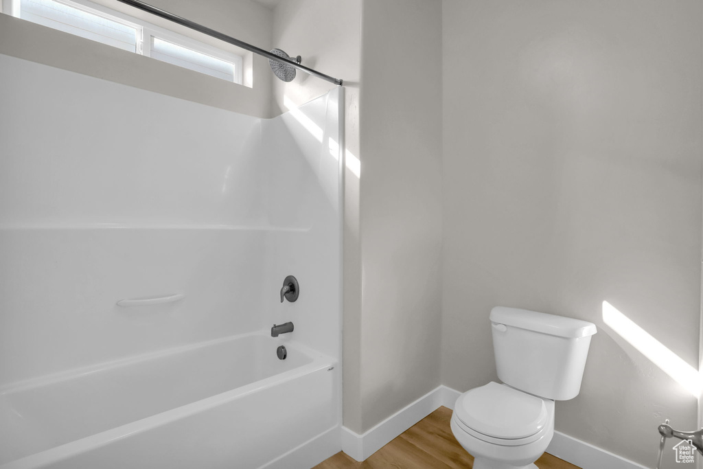 Bathroom featuring toilet, hardwood / wood-style flooring, and bathtub / shower combination