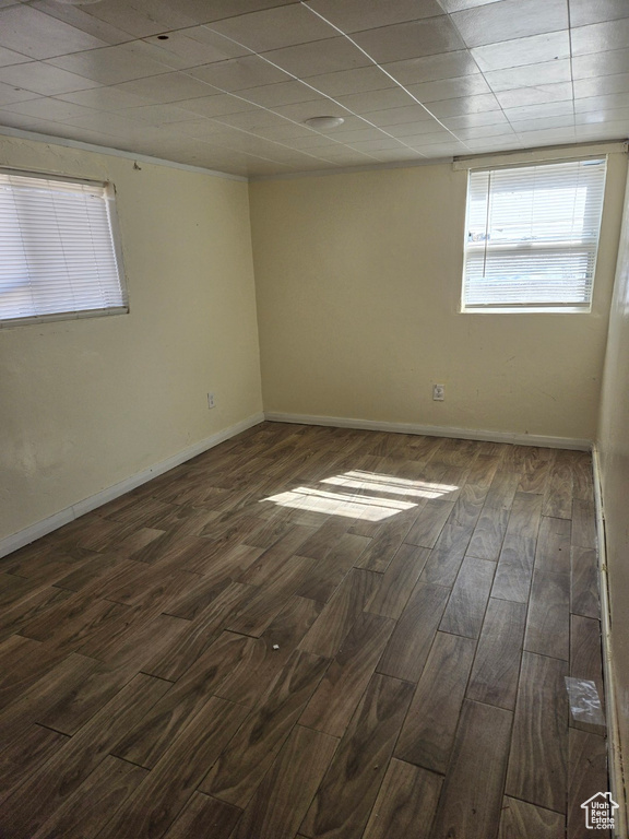 Empty room featuring dark wood-type flooring and a paneled ceiling