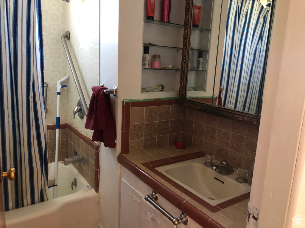Bathroom with shower / bath combo, oversized vanity, and tasteful backsplash
