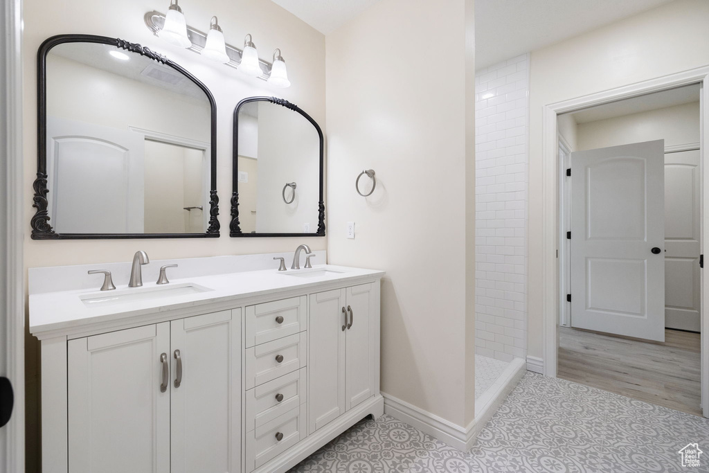 Bathroom with double vanity, tile floors, and a tile shower