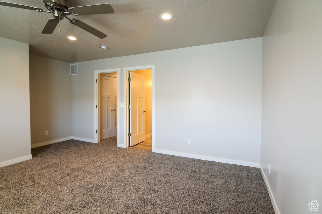 Unfurnished bedroom with ceiling fan, light carpet, and a textured ceiling