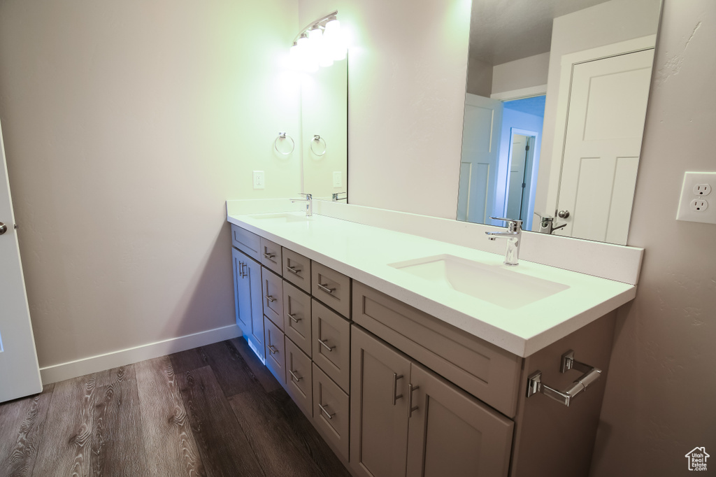 Bathroom with dual vanity and wood-type flooring