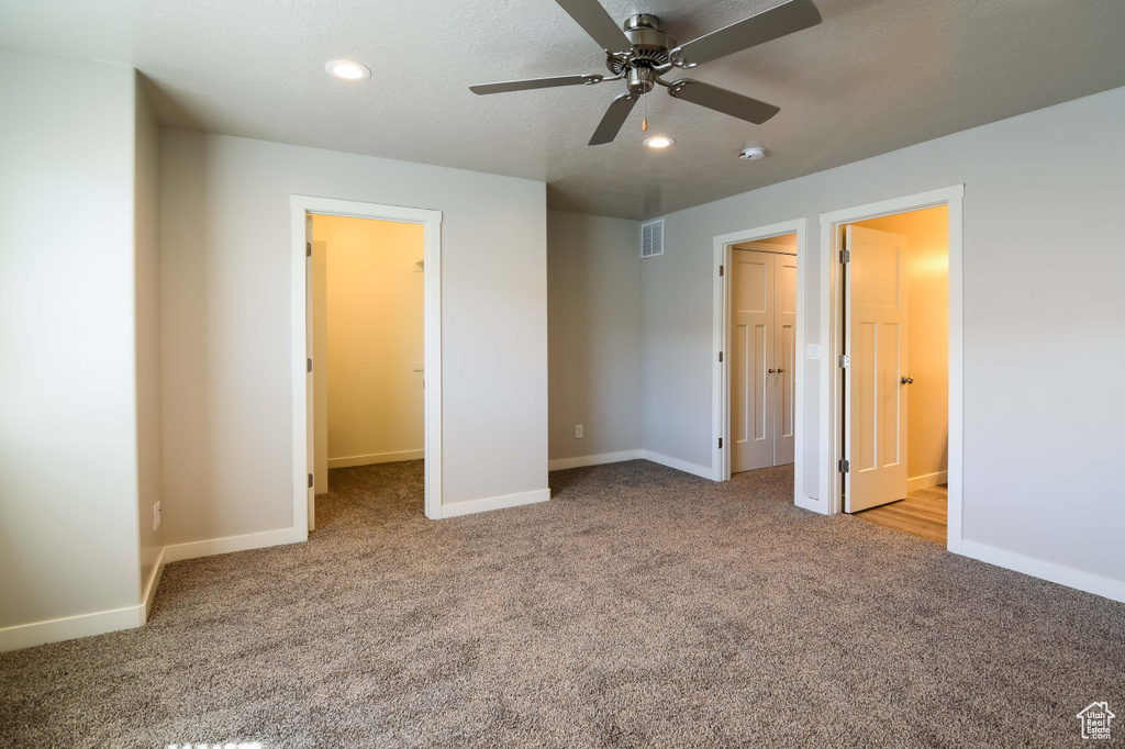 Unfurnished bedroom with ceiling fan, a closet, light colored carpet, and a spacious closet