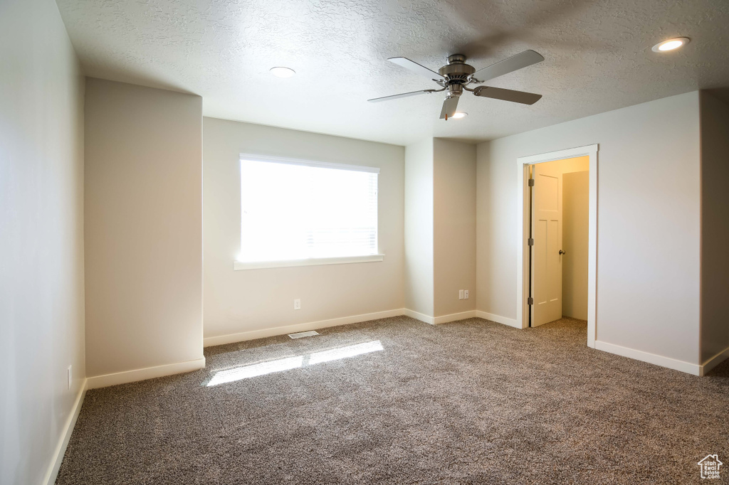 Interior space featuring a textured ceiling, carpet, and ceiling fan