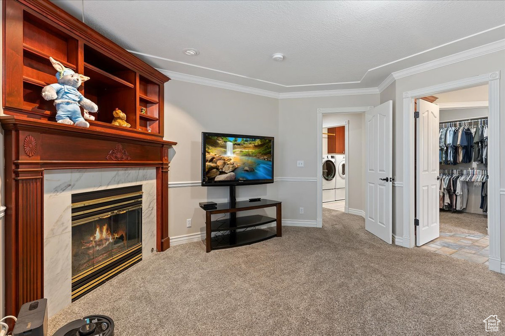 Carpeted living room with independent washer and dryer, ornamental molding, and a premium fireplace