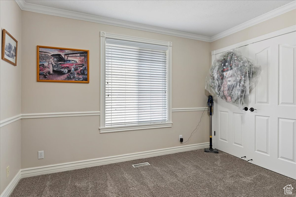 Unfurnished bedroom featuring crown molding and dark colored carpet