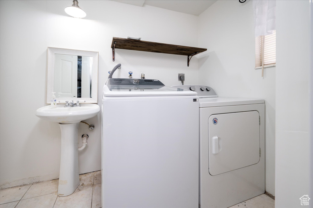 Washroom featuring hookup for an electric dryer, separate washer and dryer, light tile floors, and sink