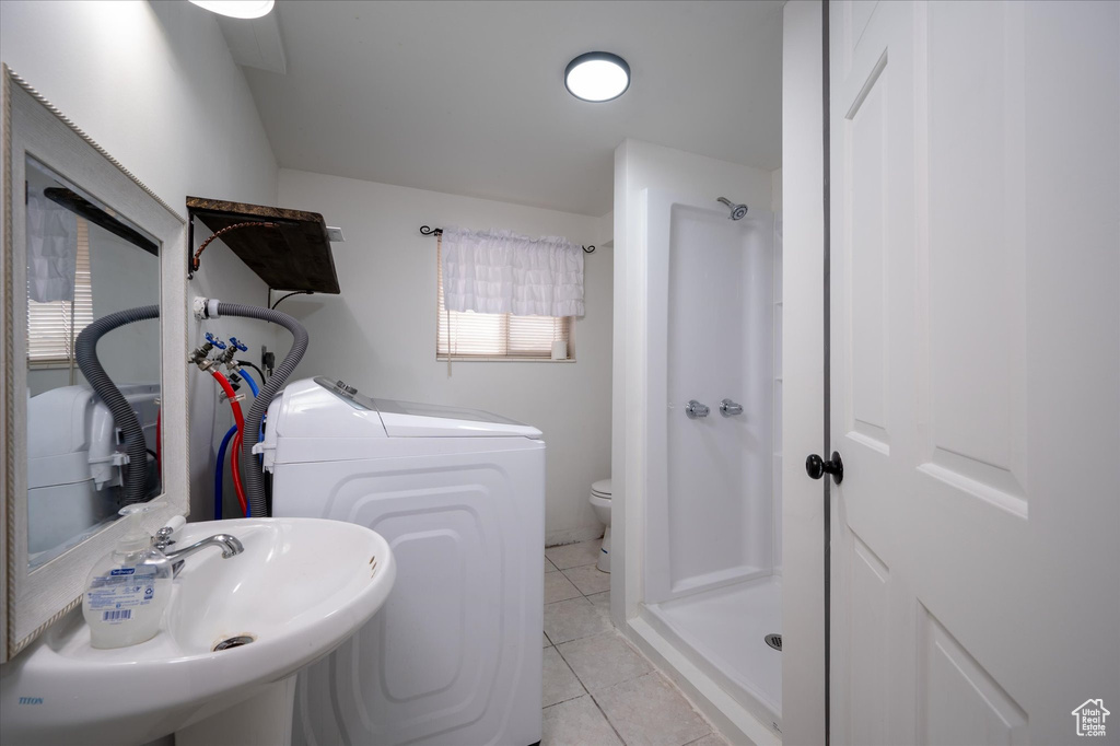 Bathroom featuring washing machine and clothes dryer, toilet, sink, and tile flooring