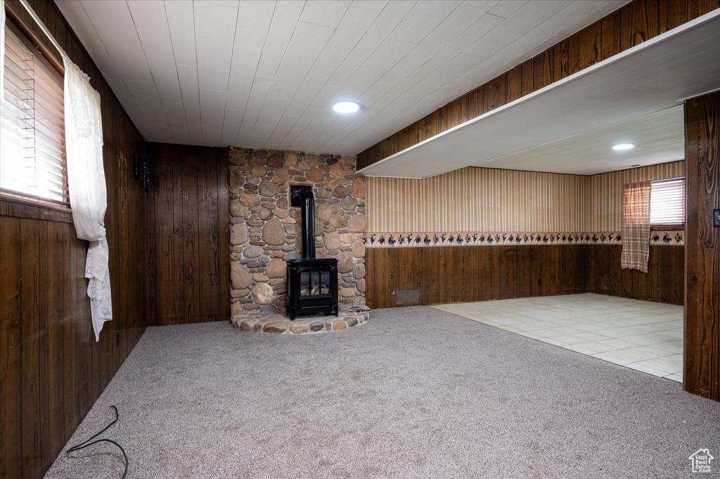 Basement with light tile floors, wood walls, and a wood stove