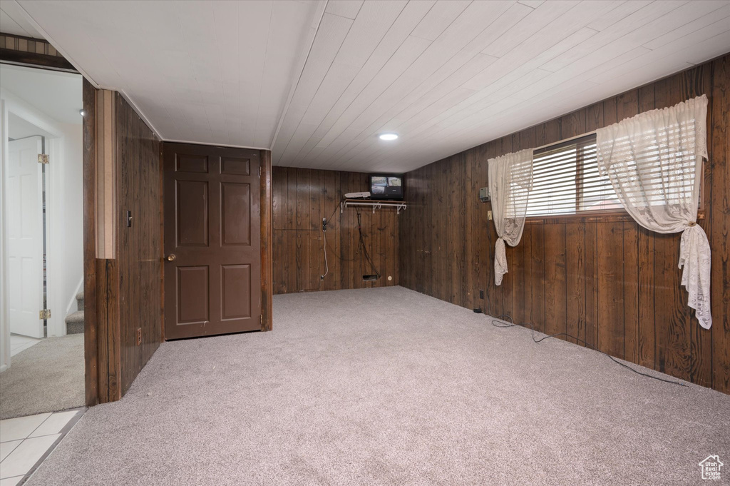 Carpeted spare room featuring wood walls