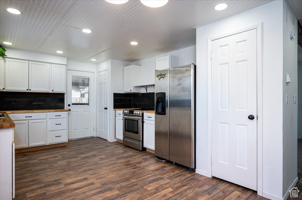 Kitchen featuring backsplash, dark hardwood / wood-style floors, butcher block countertops, stainless steel appliances, and white cabinets