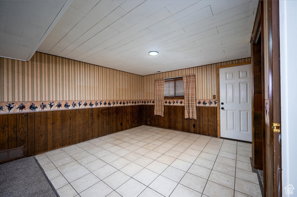 Empty room featuring wood walls and light tile floors
