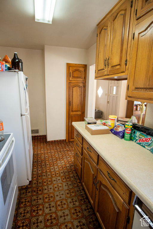 Kitchen with white fridge, range, and dark tile floors