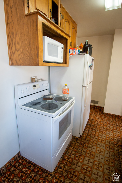 Kitchen with white appliances and dark tile flooring