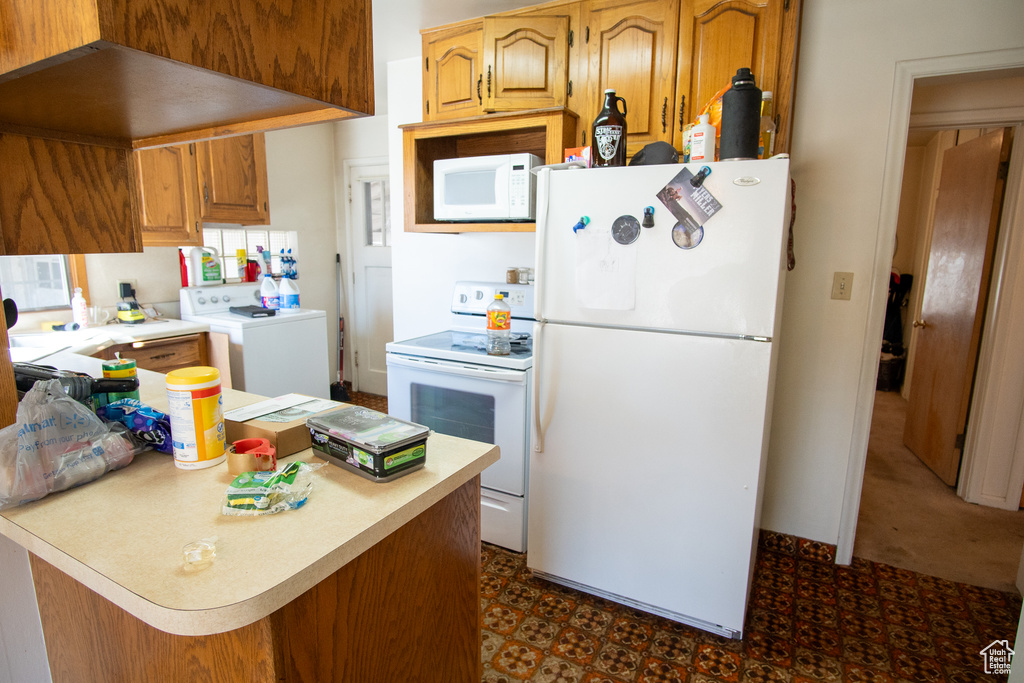 Kitchen with washer / dryer, white appliances, and dark colored carpet