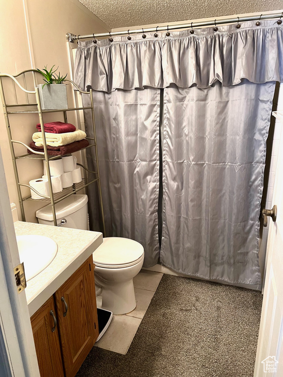 Bathroom with tile flooring, a textured ceiling, toilet, and vanity