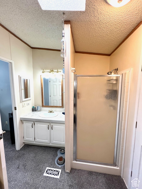 Bathroom with a shower with shower door, a textured ceiling, and large vanity
