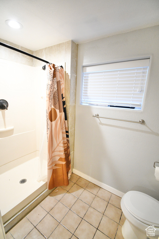 Bathroom featuring tile flooring, toilet, and a shower with shower curtain