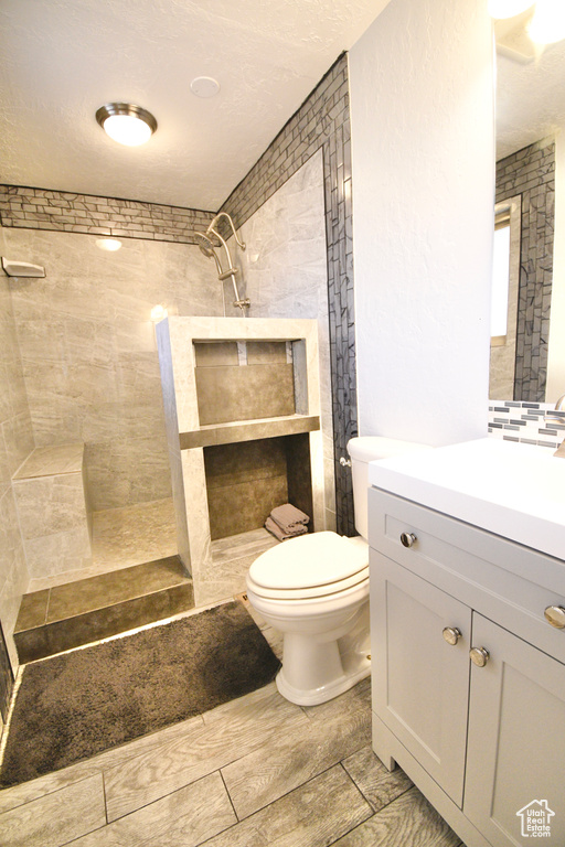 Bathroom with tile floors, toilet, vanity, and tiled shower