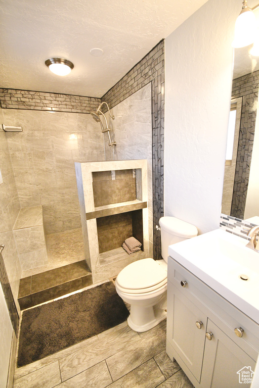 Bathroom with tile flooring, tiled shower, large vanity, and toilet