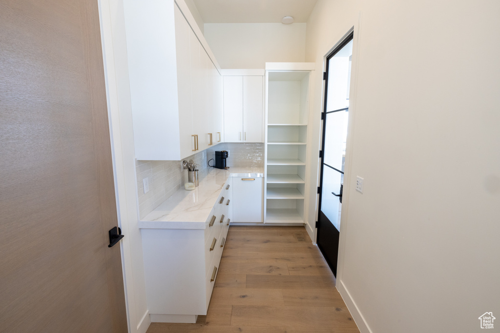 Interior space featuring white cabinetry, backsplash, and light hardwood / wood-style floors