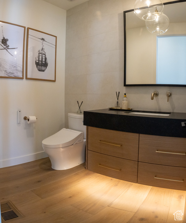 Bathroom featuring vanity, toilet, hardwood / wood-style flooring, and tile walls