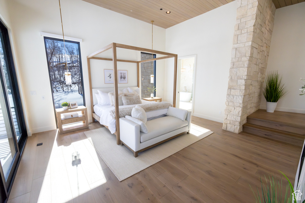 Unfurnished bedroom featuring wood ceiling, light hardwood / wood-style floors, multiple windows, and a high ceiling