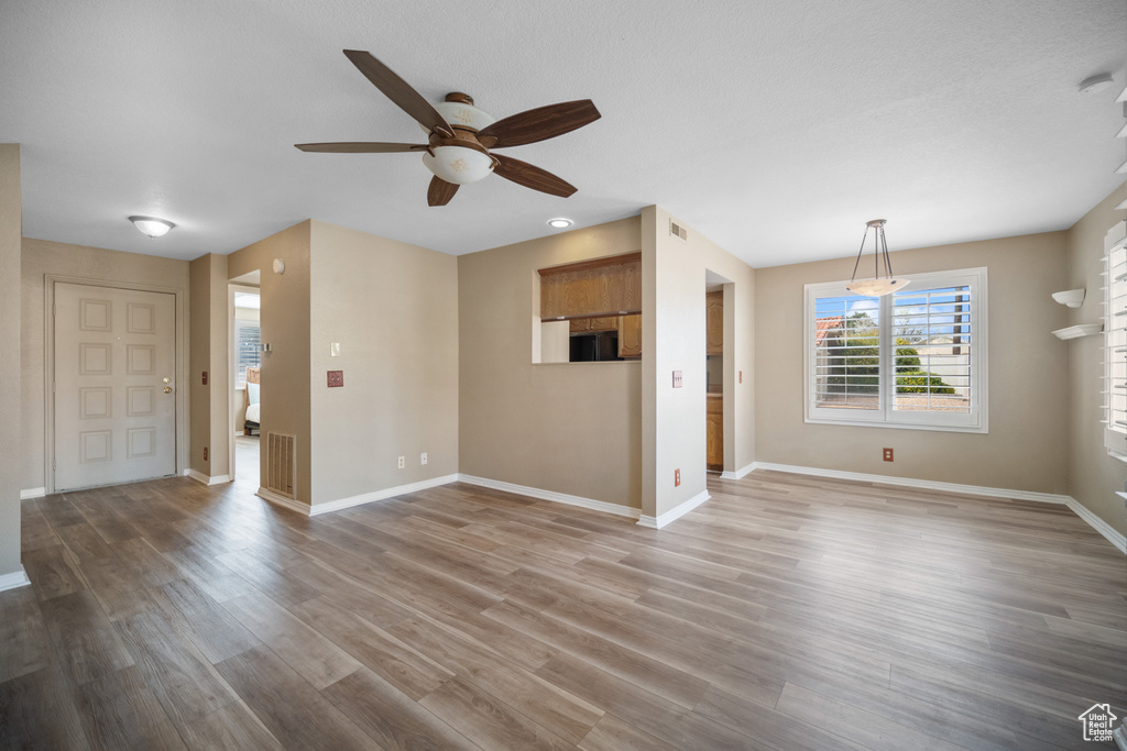 Unfurnished living room featuring hardwood / wood-style flooring and ceiling fan