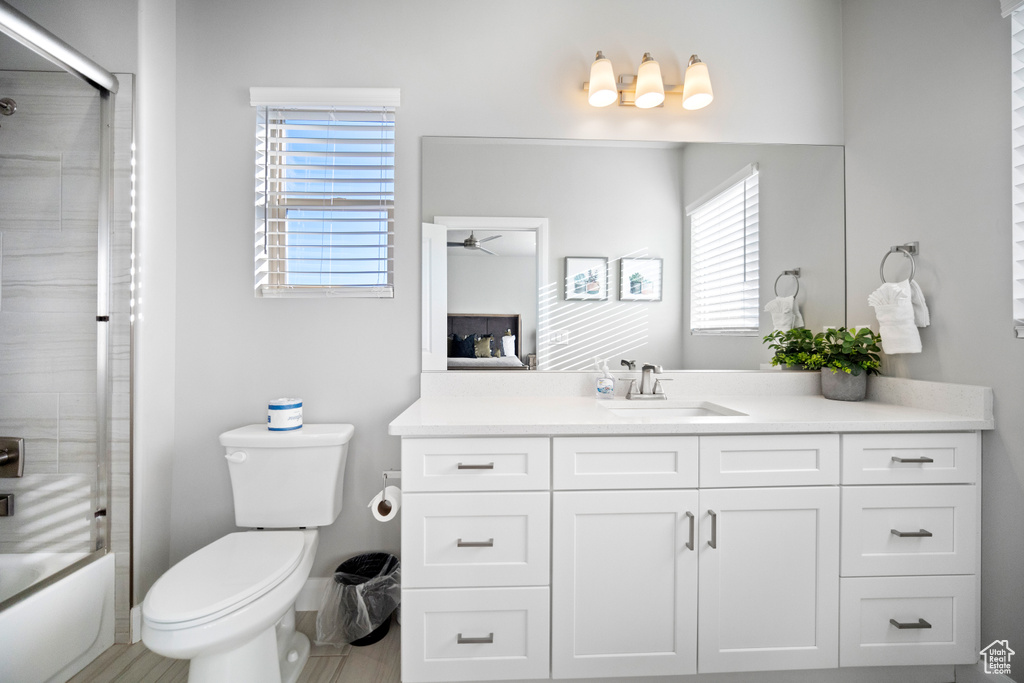 Full bathroom featuring vanity, toilet, and bath / shower combo with glass door