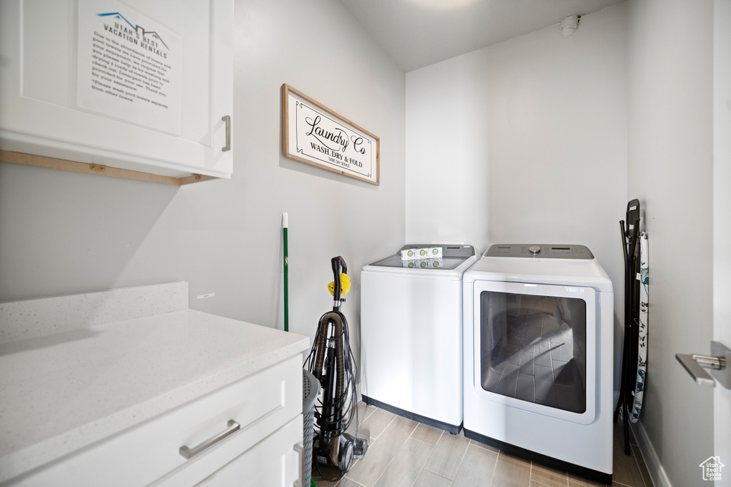 Washroom featuring cabinets, washing machine and clothes dryer, and light hardwood / wood-style floors
