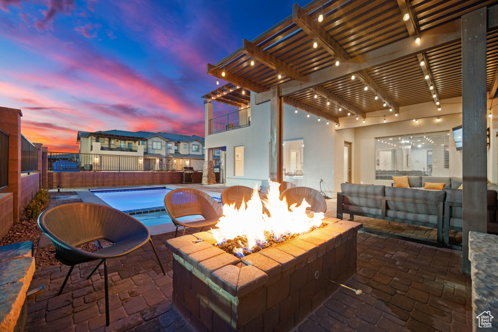 Patio terrace at dusk with an outdoor living space with a fire pit and a pergola