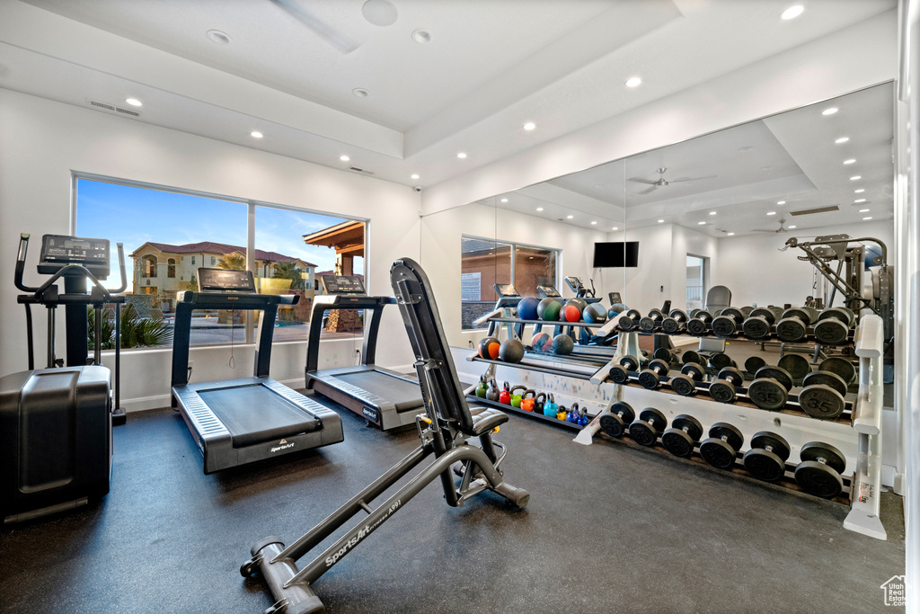 Workout area featuring a tray ceiling and ceiling fan