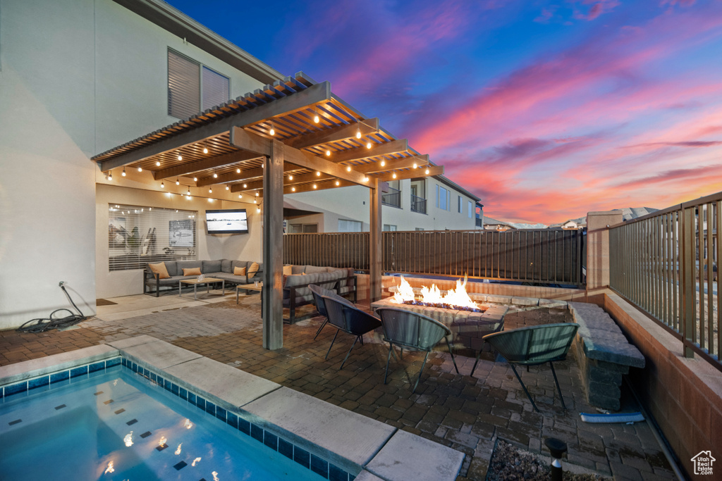 Pool at dusk featuring an outdoor living space with a fire pit, a patio, and a pergola