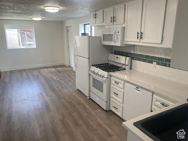 Kitchen featuring a textured ceiling, tasteful backsplash, white appliances, white cabinetry, and dark hardwood / wood-style flooring