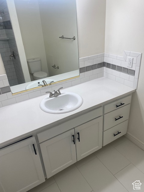 Bathroom featuring vanity with extensive cabinet space, tile floors, and toilet